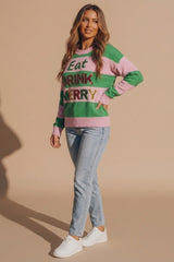 Woman wearing a green and pink striped Eat Drink Merry Christmas jumper with glitter lettering light wash jeans and white trainers from Femme Luxe